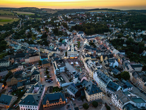 Aerial view of the market square in historic German town Schneeberg, Germany at dusk with the illuminated town hall and a golden horizon