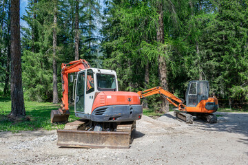 Two Small Tracked Excavators Parked near Pine Forest © Анастасия Константне