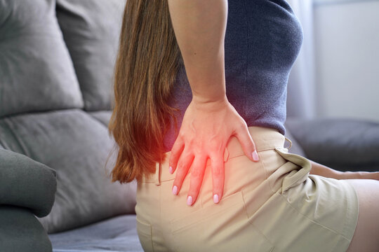 Kidney pain concept. Unrecognizable woman with hand on hip in back surprised by sudden stab of pain.