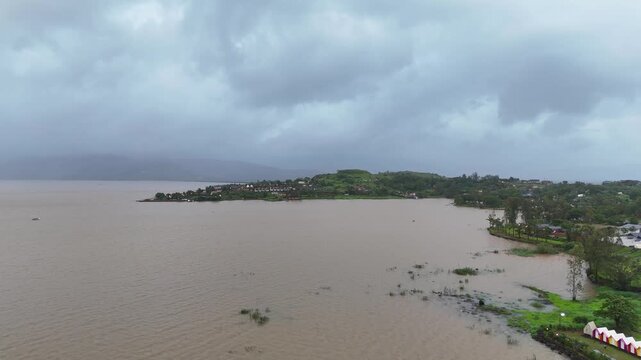 Expansive aerial drone view of scenic Pawna Lake reservoir surrounded by lush green hills under overcast monsoon sky⁠