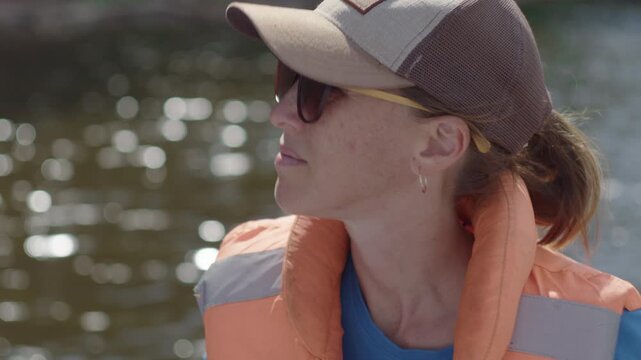 Portrait of the woman wearing lifejacket and sitting in the boat moving on the river