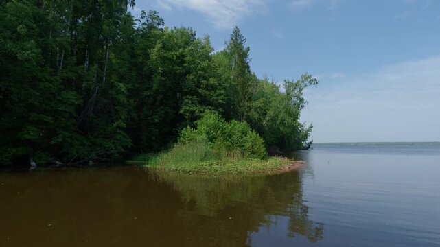 Green lush coasts of the river with brown murky water