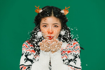 Young woman with reindeer antlers blowing snow for Christmas portrait © TrieuMai