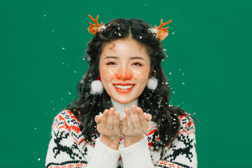 Smiling young woman in Christmas sweater with reindeer antlers and falling snow © TrieuMai