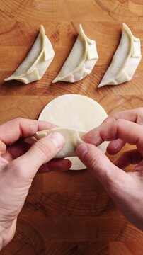 Chef quickly closes gyoza by pressing dough edges. Gyoza stays closed and keeps filling inside during frying or steaming. Fast gyoza folding works for cooking class, restaurant prep or recipe video.