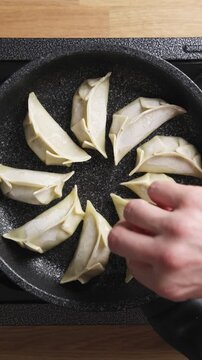Hand shows crisp golden bottom of fried gyoza to camera. Gyoza video explains how hot pan and oil make even brown crust. Use gyoza video for cooking lesson, food blog, online class or recipe guide.