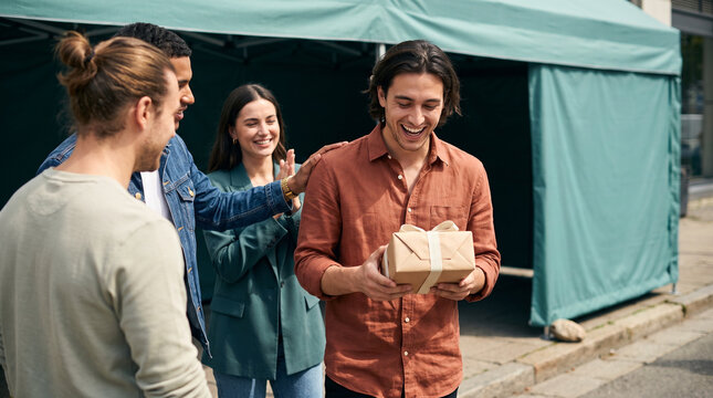 Young adults celebrating a gift at an outdoor gathering event  