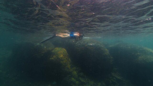 Young slim woman swims underwater, freediving and snorkeling in the sea near the coral reef near the island of Ilha Grande in Brazil