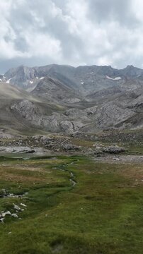 Slow cinematic push-in through a peaceful alpine valley with a winding creek and majestic mountains.