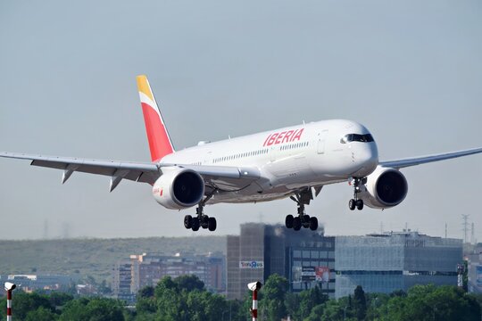MADRID, SPAIN - MAY 29, 2026: Airbus A350 900 of Iberia, the flag carrier of Spain, on final approach with the landing gear down, office buildings and a hazy skyline behind the runway