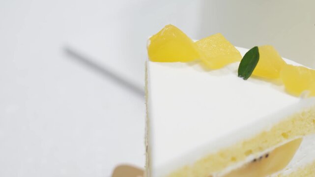 A detailed close up macro shot of a delicious sponge cake slice layered with fluffy white whipped cream and fresh tropical fruit chunks like mango and kiwi. This aesthetic gourmet dessert is perfect f