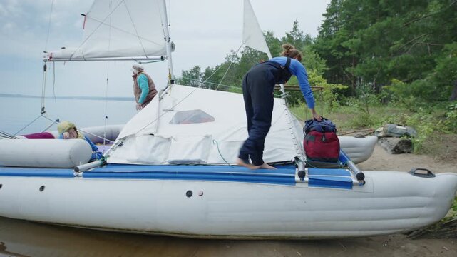 Woman with kid walk on the sailing boat beached on the wild area