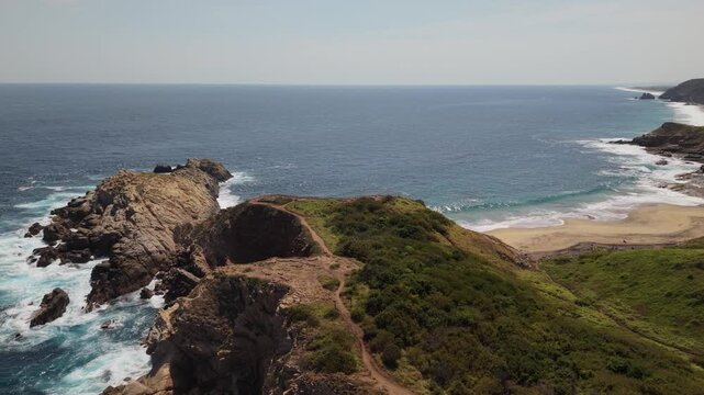4K drone footage moving smoothly from right to left over Punta Cometa in Oaxaca, revealing coastal vegetation, a hidden beach, ocean views and walking trails leading to a scenic sunset viewpoint.