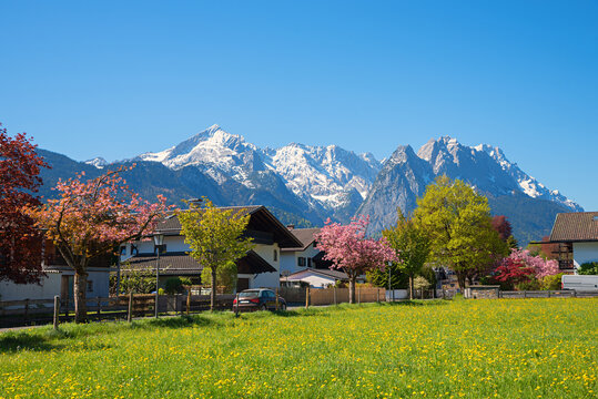 Idyllic town of Garmisch-Partenkirchen with a view of the Alpspitze and Zugspitze in spring.