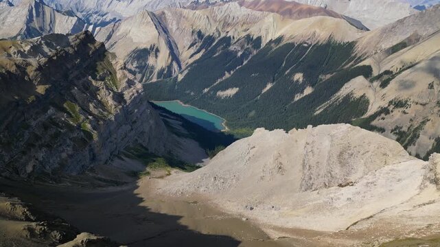 Cinematic aerial high angle view of an isolated turquoise glacial lake in a deep mountain valley, Canadian Rockies Alberta Canada