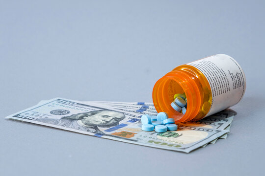 RX Pills Blue spilled on hundred dollar bills. Space on top.
