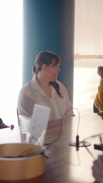 Vertical. Professionals gather around a table in a contemporary office setting, actively participating in a productive meeting, fostering teamwork and innovation
