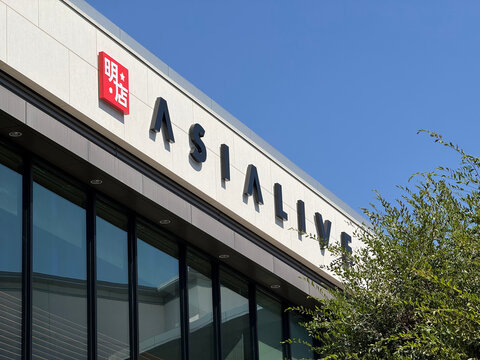 Modern retail storefront with a red sign, large facade lettering, glass windows and a leafy tree beneath a clear blue sky - Santa Clara, California, USA - August 19, 2026