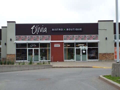 Gatineau, Quebec, Canada &ndash; June 26, 2026: The storefront of "Olivia Bistro Boutique" features large glass windows, double doors labeled "Sortie" and "Entr&eacute;e," and a decorative floral awning band at 59