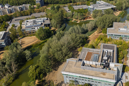 Modern Office Buildings Surrounded by Green Trees and a Small Canal in Daylight