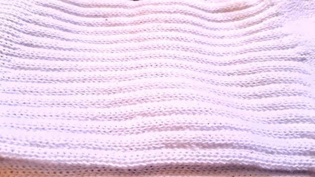 Soft white knitted fabric showing detailed rhythmic horizontal ribbed wool texture