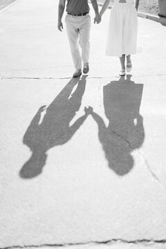 Black and white couple walking holding hands shadows