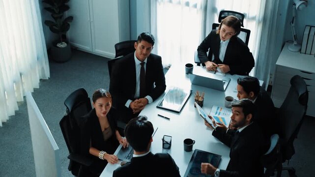 Top view of businessman present idea and pointing at whiteboard while executive manager listen presentation. Skilled investors raised hand to ask questions. Smart team working together. Directorate.