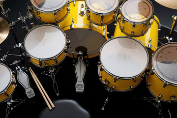 Obraz premium Overhead view of bright yellow drum kit on dark stage floor. Professional percussion set includes snare, tom, bass drum with pedals, sticks. Musician equipment prepared for rock concert, band