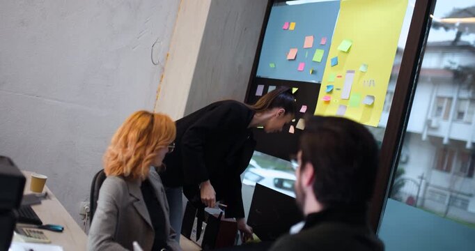 Presentation in an office with sticky notes as a team member explains a project idea while speaking to colleagues during a meeting in the afternoon