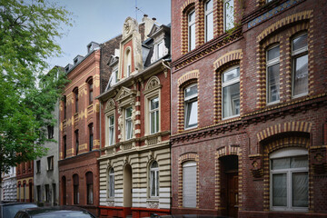 Fototapeta premium Street view of protected historic residential buildings featuring red and yellow brick facades in Cologne Ehrenfeld, Germany. Classic architecture.