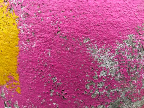 Vivid magenta paint with yellow stripe on gritty concrete texture