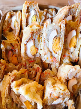 Deep-fried kwek kwek quail egg fritters sliced open to reveal golden yolk, crispy orange batter, street food close-up