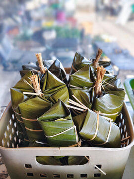 Banana leaf wrapped food parcels tied with bamboo twine displayed in a market basket, vibrant green traditional packaging