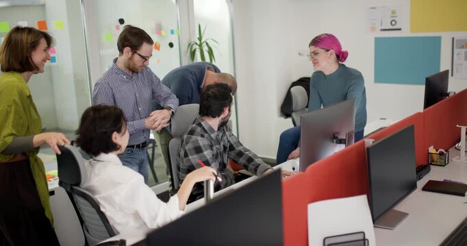 Team members discuss ideas and projects in a bright office while collaborating at their desks during a busy workday