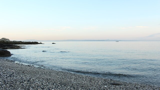 早朝の静かな礫浜と穏やかな海面
