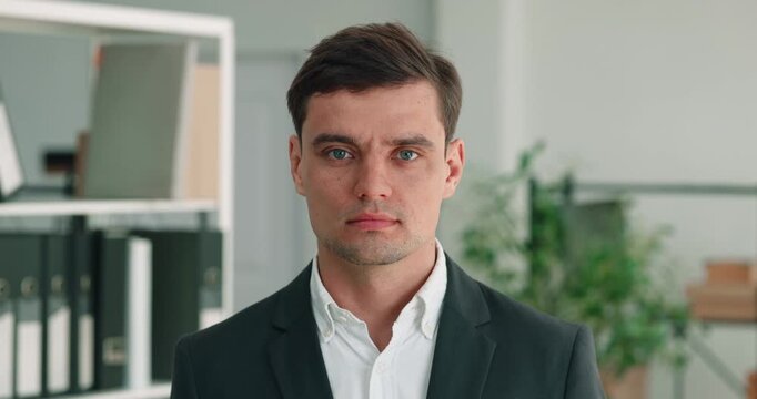 Portrait of businessman in office shows calm face and direct gaze. Caucasian businessman turns head as looks ahead with quiet confidence in formal office pose