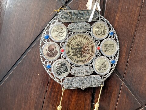 Ornate circular metal wall hanging featuring Islamic calligraphy and Arabic script decorations.