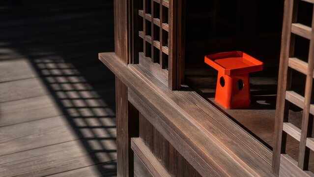 神社の授与所の格子窓と朱色の三方 木の建具と光の影
