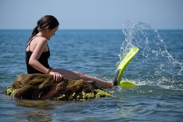 Girl sitting on a rock in the sea with flippers © Andy