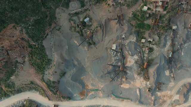 A large scale earthworks extraction facility, Industrial sorting machines and conveyor belts organizing piles of crushed gravel and sand in a mining site