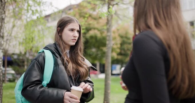 Two Teenage Girls Chatting Over Coffee in a Park