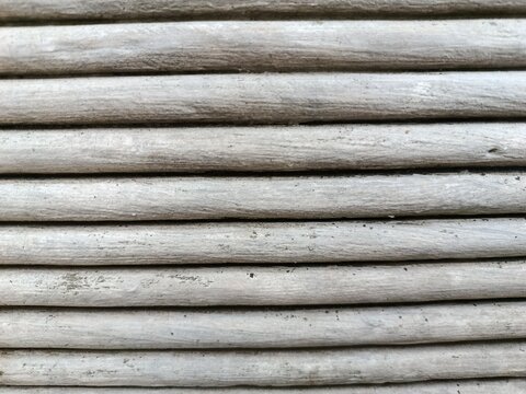 oA close-up shot of a textured surface featuring horizontal grey wooden slats arranged parallel to each other. The weathered wood shows subtle imperfections, grain details, and dark grooves between th