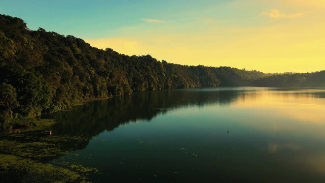 Scenic view of Gubug Temple at misty Lake Tamblingan surrounded by lush rainforest in Bedugul, Bali, Indonesia