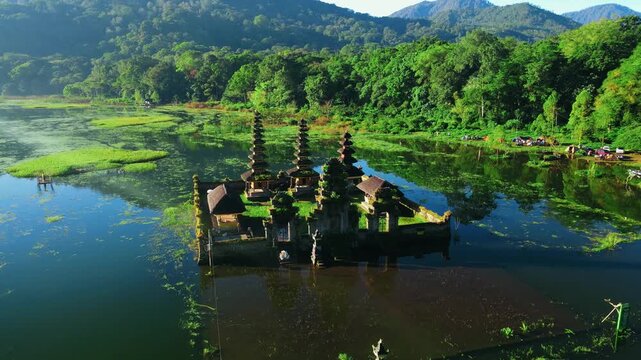 Scenic view of Gubug Temple at misty Lake Tamblingan surrounded by lush rainforest in Bedugul, Bali, Indonesia
