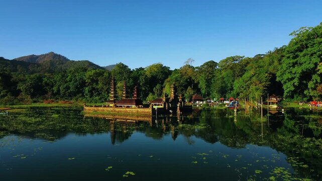Scenic view of Gubug Temple at misty Lake Tamblingan surrounded by lush rainforest in Bedugul, Bali, Indonesia