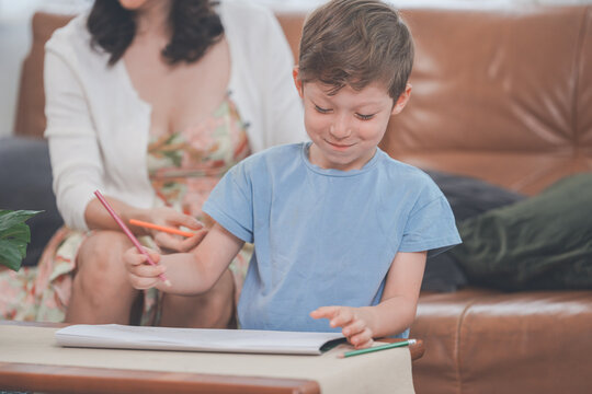 The young family guide their child through a drawing activity in a bright, cosy living room.