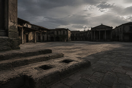 Empty ancient market square with stone steps showing indentations where a pillory once stood.