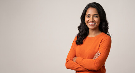 Fototapeta premium Portrait of a confident smiling young professional woman with crossed arms looking at camera standing on grey background with copy space