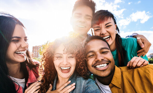 Multicultural friends taking selfie together pic with mobile phone - People having fun hugging outdoors - Youth lifestyle and friendship concept