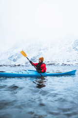 Naklejka premium Woman paddling a kayak in Lofoten, Norway